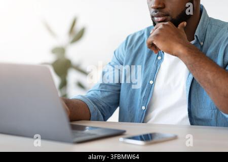 Busy Black Entrepreneur Working With Laptop At Office, Focused On Screen Stock Photo