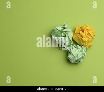 Three crumpled balls of colored paper on a green background, copy space Stock Photo