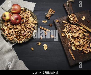 Dried pieces of apples in an iron plate and on a brown wooden board, top view, empty space in the middle Stock Photo