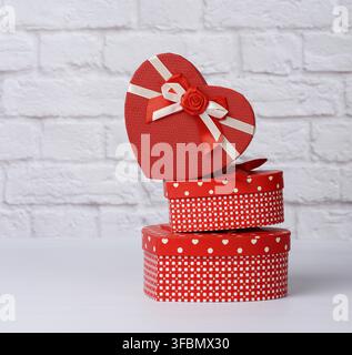 Stack of various red boxes with gifts on white background, festive backdrop Stock Photo
