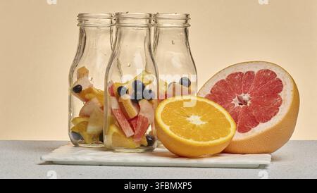 Empty glass bottles filled with citrus slices and blueberries Stock Photo