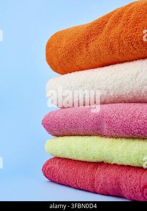 Stack of colored cotton terry folded towels on a blue background, close up Stock Photo