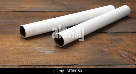 White paper tube from a roll of kitchen towels, object on a brown wooden background, top view Stock Photo