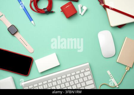 Keyboard, golden power bank with cable, red smartphone with blank black screen, headphones, blank paper business cards and wireless mouse on green bac Stock Photo
