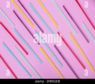 Colorful plastic tube with white polka dots for drinks scattered on a pink background Stock Photo