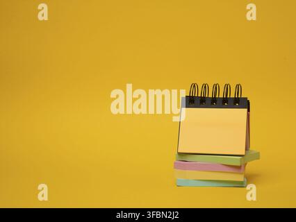 Stack of paper multi-colored stickers on a yellow background, copy space Stock Photo