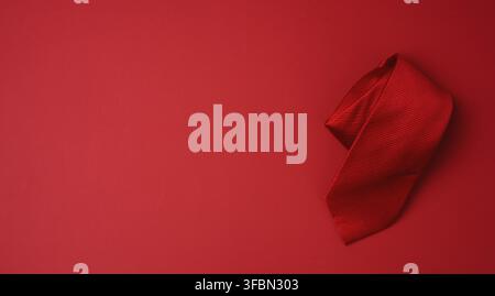 Twisted silk red tie on a red background, copy space Stock Photo
