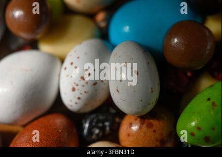 Brightly colored decorative eggs rest among candies, embodying the spirit of spring celebrations. Stock Photo