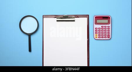 Pink calculator, folder with blank white sheets and black magnifier on a blue background. Banner for business, top view Stock Photo