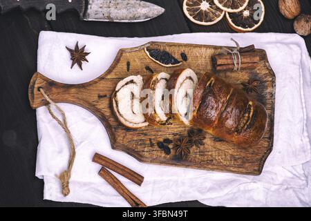Baked roll with cinnamon and nuts on a wooden board, top view Stock Photo
