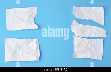Crumpled white sheet of paper torn on a blue background. Paper piece torn edge Stock Photo