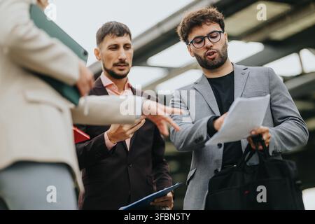 Business colleagues reviewing documents and discussing plans during an outdoor meeting Stock Photo