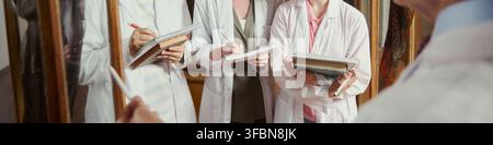 Header of diverse group of young adult medical students in lab coats taking notes during lecture. Image is suitable for medical education marketing and university recruitment materials Stock Photo