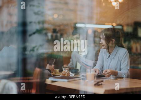 Business colleagues having a casual meeting outside at a cafe seen through a window reflection Stock Photo