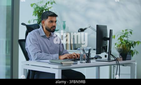Focused concentrated Arabian business man looking at computer working with software in office Indian boss businessman worker serious male look in Stock Photo