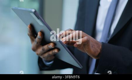 Close up male hands holding digital tablet unrecognizable African American business man using wirless device in office unknown ethnic businessman male Stock Photo