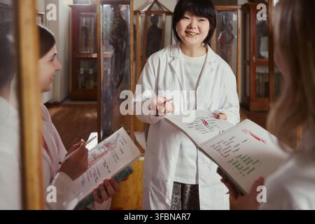 Portrait of Asian female medical student smiling during group discussion in anatomy museum. Image suitable for medical school brochures and higher education marketing Stock Photo