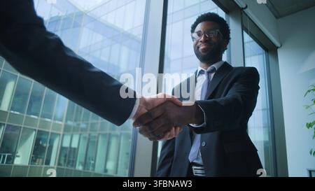 African American business man communicate shaking hands with unknown male in corporate office. Ethnic businessman consulting client handshaking two Stock Photo