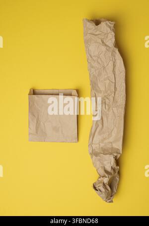 Brown paper craft bags for food packaging on a yellow background, top view Stock Photo