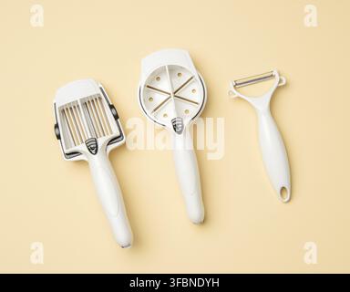 Various plastic knives for cutting vegetables, fruits on a beige background, top view Stock Photo