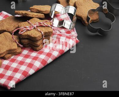 Baked star shaped gingerbread cookies on black table, christmas baked goods Stock Photo