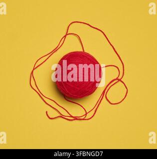 Ball of red woolen thread on yellow background, top view Stock Photo