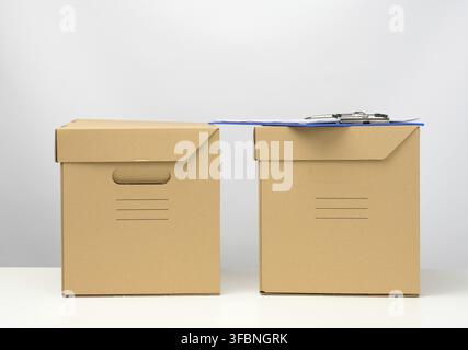Two cardboard boxes made of brown corrugated cardboard are on a white table, moving, goods delivery Stock Photo