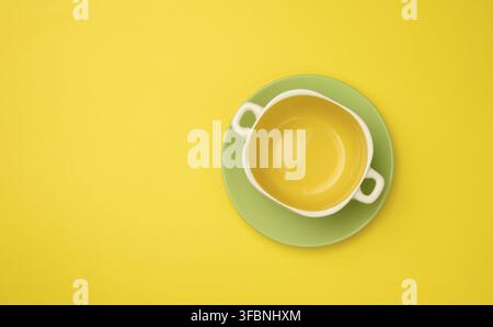 Empty yellow soup plate on a yellow bacground, top view Stock Photo