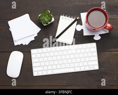 White wireless keyboard and mouse on a wooden brown table, top view, workplace Stock Photo