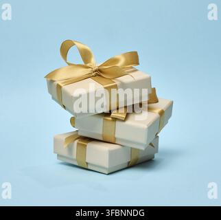 Stack of gift boxes with golden silk bows on blue background Stock Photo