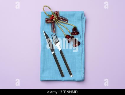 Metal knife and fork on a blue napkin and christmas decor, top view Stock Photo