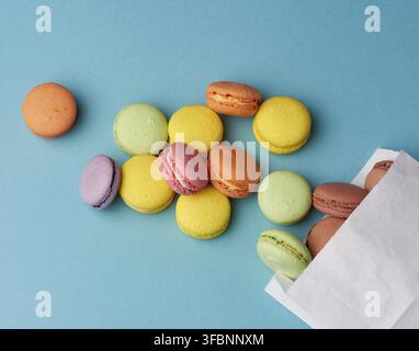 Stack of multi-colored round baked macarons cakes on a blue background, close up Stock Photo