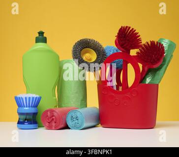 Plastic basket with brushes, disinfectant in a bottle on a yellow background Stock Photo