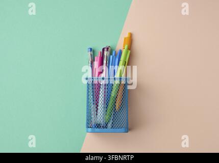 Blue metal container for stationery, inside multi-colored plastic pens, top view Stock Photo