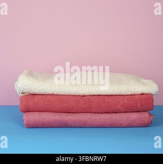 Stack of pink folded towels on a blue background, set for a bath Stock Photo