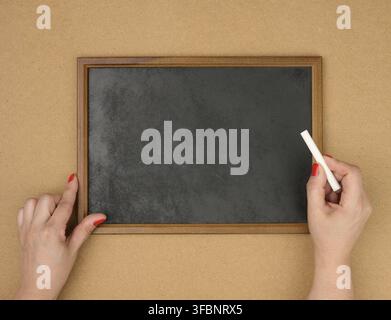 Female hands and empty rectangular brown wooden frame on a brown background, copy space Stock Photo
