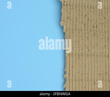 Brown corrugated cardboard with torn edges on a light blue background, copy space Stock Photo