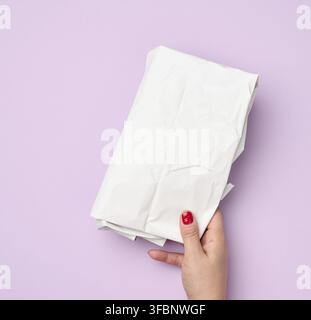 Hand hold folded wrapping crumpled white paper on purple background Stock Photo