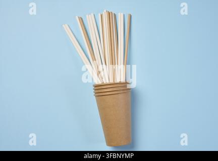 Paper cocktail straws and paper cups on a blue background, top view Stock Photo