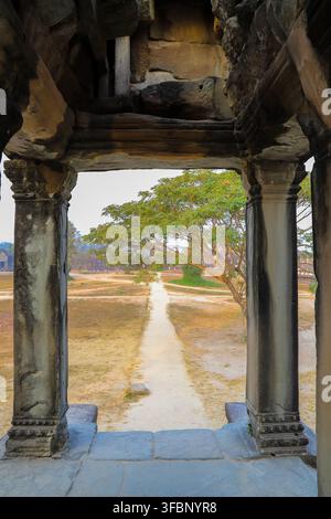Krong Siem Reap, Cambodia - 04 February 2020: View of Angkor Wat framed by ancient stone pillars, with a sandy path leading through the temple grounds Stock Photo