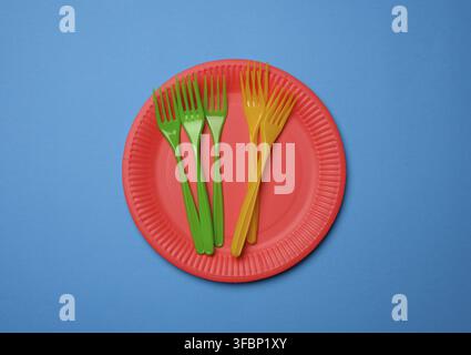 Green, orange plastic forks and empty red paper disposable plates on a blue background, set Stock Photo