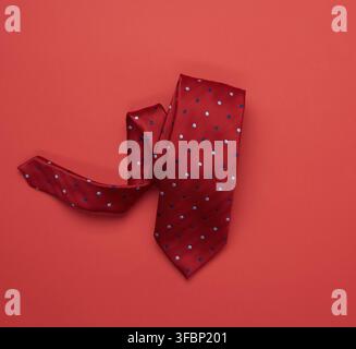 Twisted silk red tie on red background, top view Stock Photo