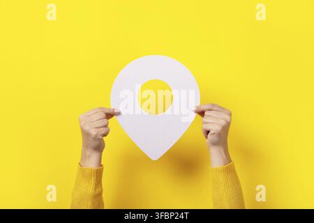 White map pointer 3d pin in hand over yellow background Stock Photo