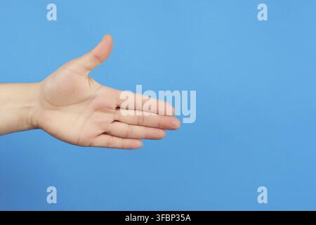 Outstretched hand of man, open hand, part of the body on a blue background, close up Stock Photo