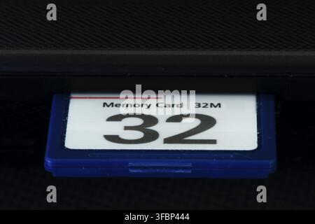 Extreme close up detail of old and dated low storage blue 32 MB micro or macro compact flash memory card plugged into laptop Stock Photo