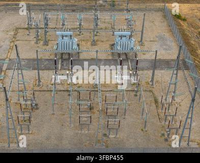 Aerial view of electrical substation infrastructure with two large power transformers, high voltage insulators, switchgear and transmission equipment Stock Photo