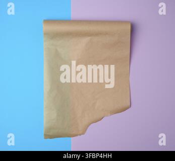 Unwrapped a roll of brown parchment paper on a colored background, place for text Stock Photo