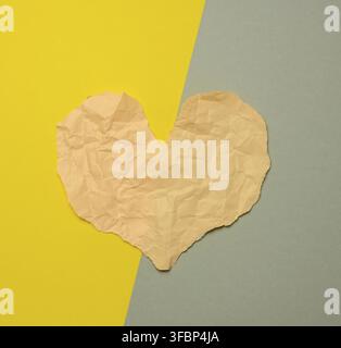 Heart made of torn paper on a gray-yellow background, top view Stock Photo