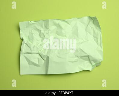 Blank crumpled green sheet of paper on a green background, copy space Stock Photo