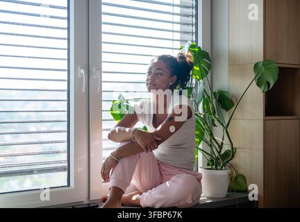 Female diabetes patient with CGM sensor in bright apartment Stock Photo